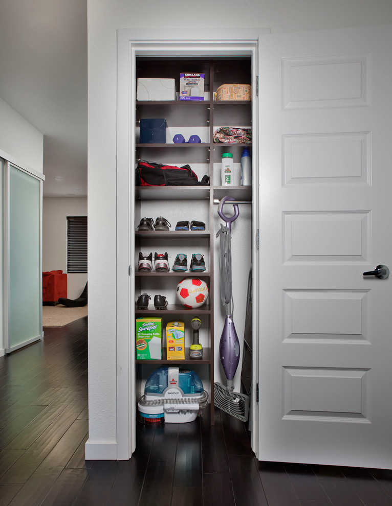 Example of a small minimalist reach-in closet design in Toronto with dark wood cabinets