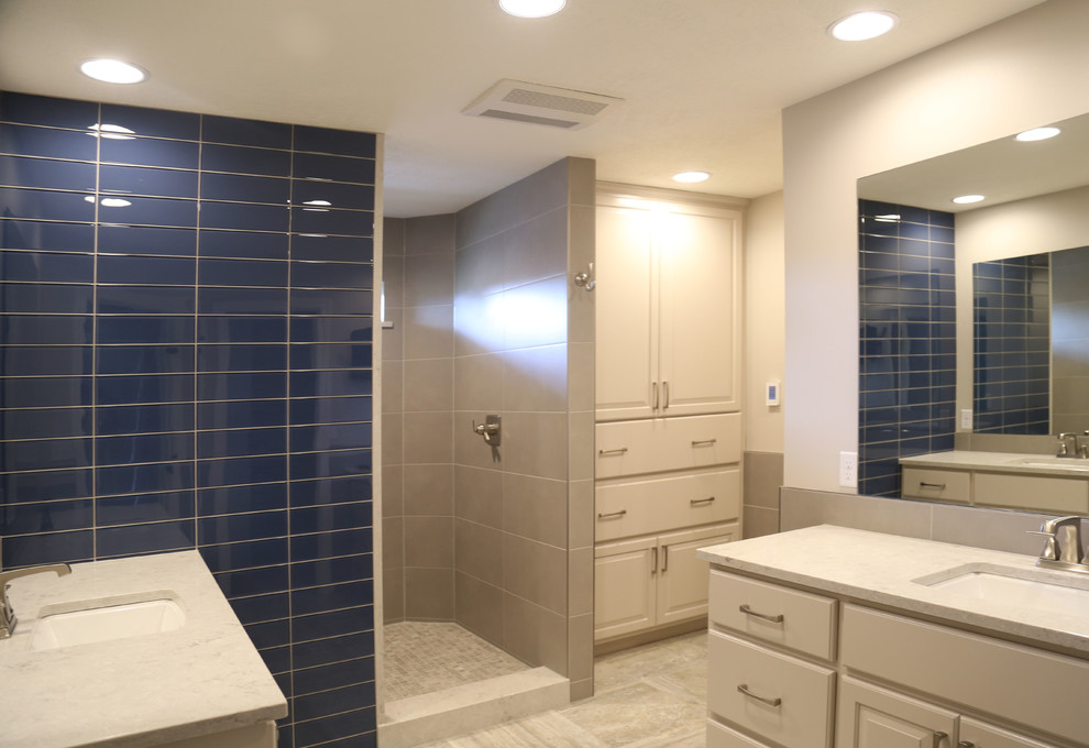 Inspiration for a mid-sized transitional master white tile and porcelain tile porcelain tile doorless shower remodel with raised-panel cabinets, white cabinets, a two-piece toilet, white walls, an undermount sink and quartzite countertops