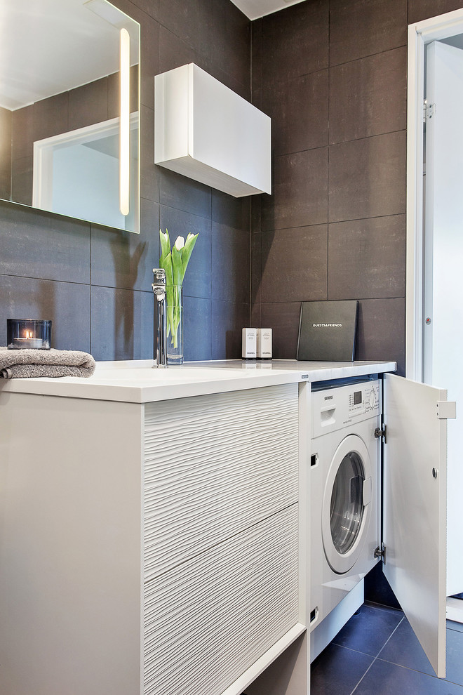 This is an example of a small contemporary single-wall laundry room in Stockholm with flat-panel cabinets, white cabinets, brown walls, a side-by-side washer and dryer, laminate benchtops, ceramic floors and white benchtop.
