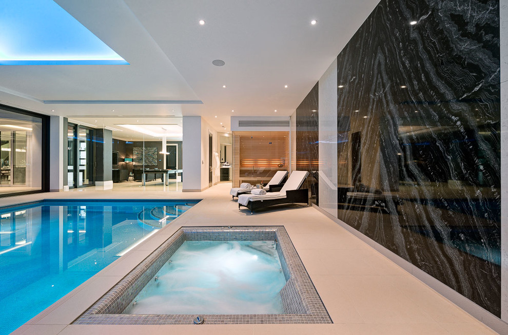 This is an example of a contemporary indoor rectangular pool in Surrey with a hot tub.