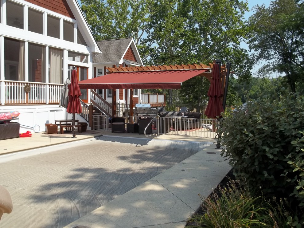 Photo of a mid-sized traditional backyard patio in Indianapolis with an outdoor kitchen, stamped concrete and an awning.