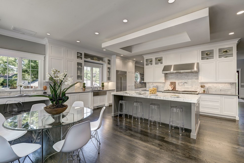 Photo of an expansive contemporary l-shaped open plan kitchen in DC Metro with a farmhouse sink, shaker cabinets, white cabinets, quartz benchtops, multi-coloured splashback, marble splashback, stainless steel appliances, dark hardwood floors, with island, brown floor and grey benchtop.