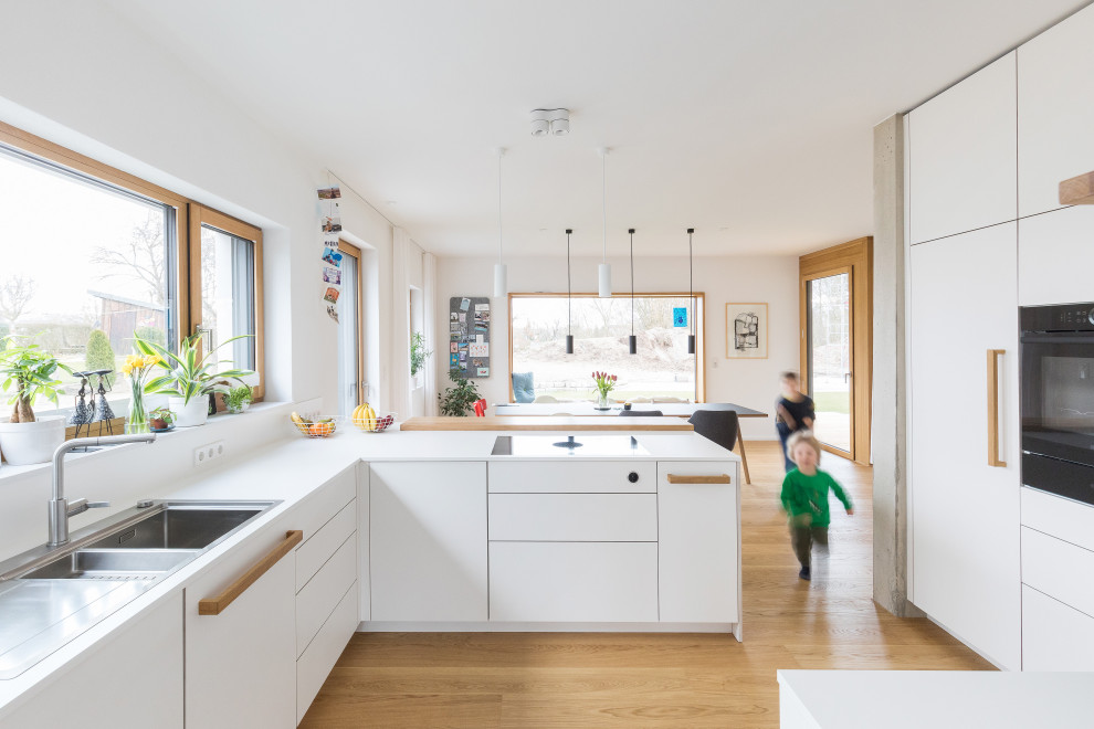 Ejemplo de cocinas en L nórdica grande abierta con puertas de armario blancas, salpicadero blanco, bandeja y barras de cocina