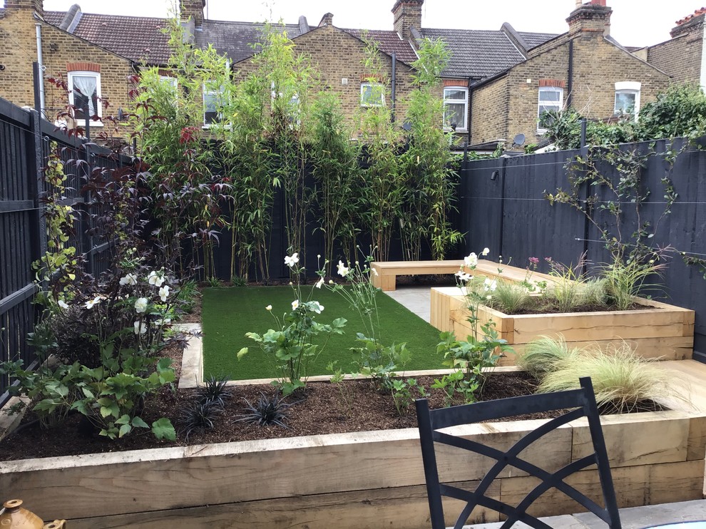 Mid-sized contemporary backyard partial sun garden in London with with raised garden bed and natural stone pavers for summer.