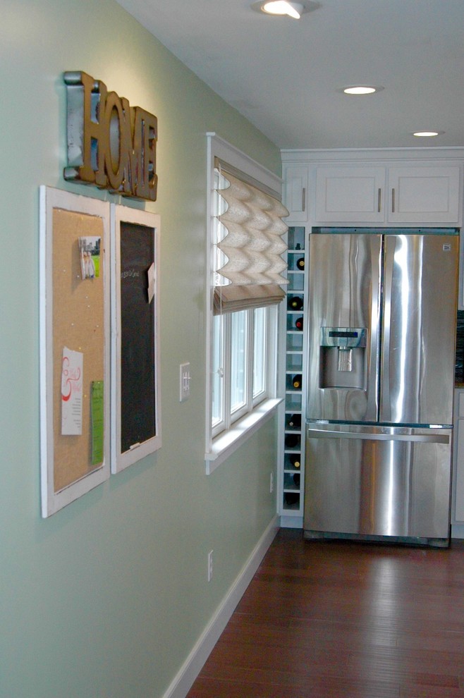 Example of a mid-sized transitional l-shaped medium tone wood floor and brown floor enclosed kitchen design in Boston with an undermount sink, recessed-panel cabinets, white cabinets, granite countertops, multicolored backsplash, glass tile backsplash, stainless steel appliances and an island