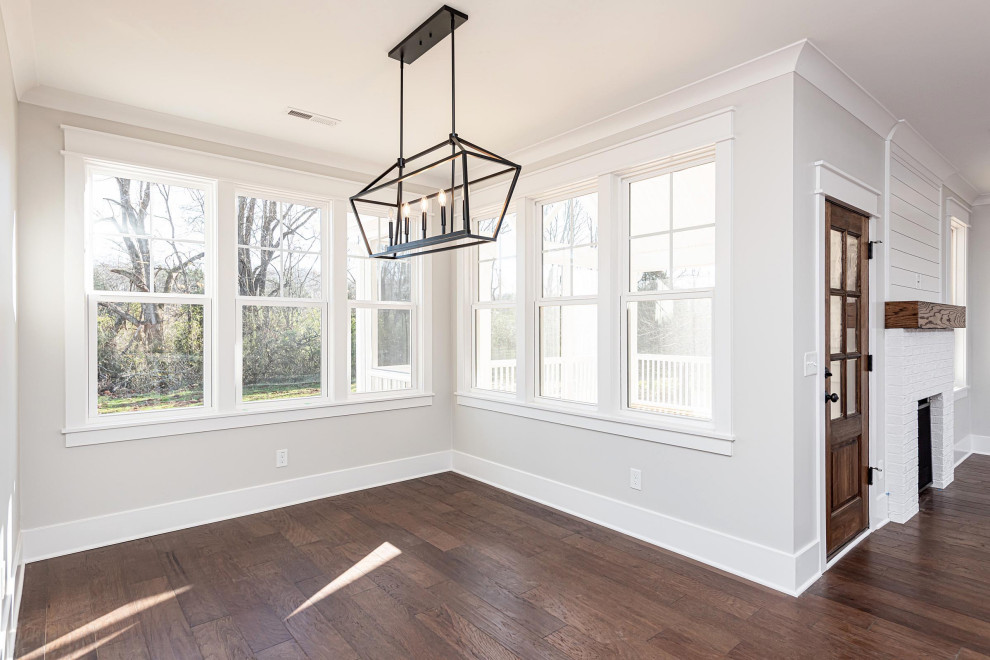 Mid-sized traditional dining room in Raleigh with white walls, medium hardwood floors, a standard fireplace, a brick fireplace surround and brown floor.