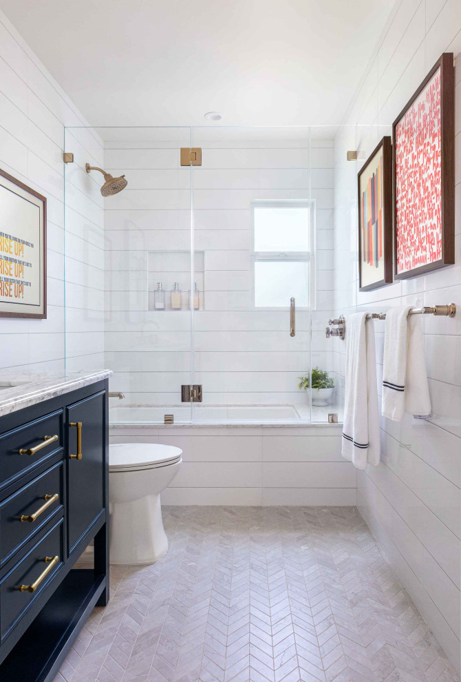 Inspiration for a mid-sized timeless 3/4 white tile and ceramic tile single-sink tub/shower combo remodel in San Francisco with shaker cabinets, blue cabinets, an undermount tub, a two-piece toilet, white walls, quartz countertops, a hinged shower door, gray countertops, a niche and a freestanding vanity