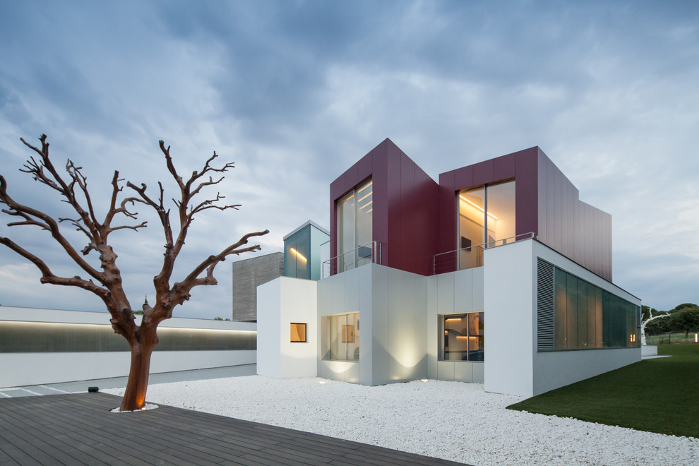 Expansive contemporary two-storey red exterior in Madrid with mixed siding and a flat roof.