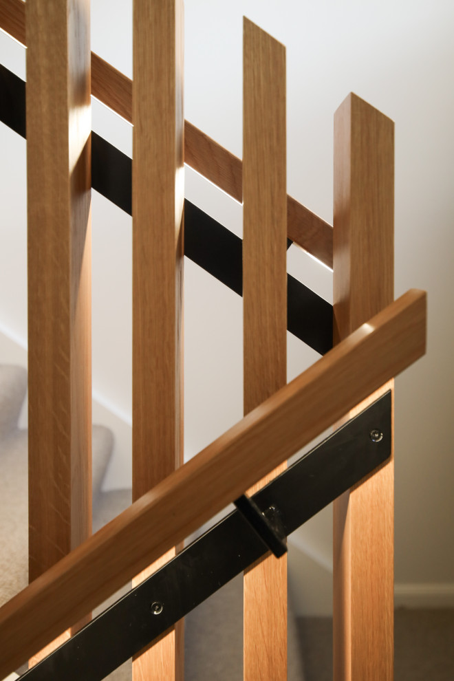 Modelo de escalera recta actual de tamaño medio con escalones enmoquetados, barandilla de madera y papel pintado