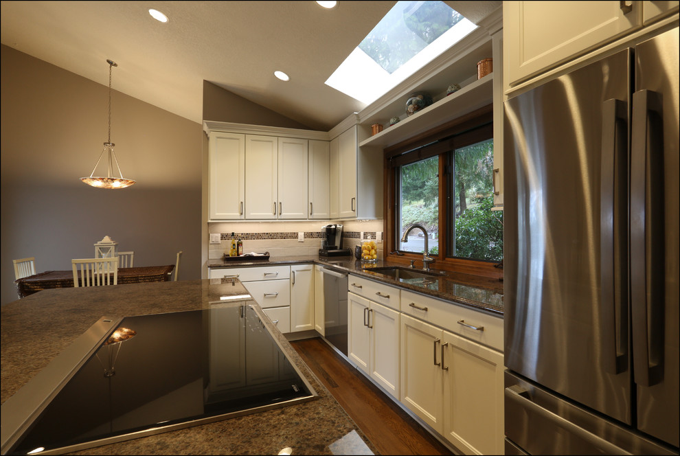 Design ideas for a mid-sized transitional kitchen in Portland with an undermount sink, recessed-panel cabinets, white cabinets, granite benchtops, brown splashback, glass tile splashback, stainless steel appliances, medium hardwood floors, with island, brown floor and brown benchtop.
