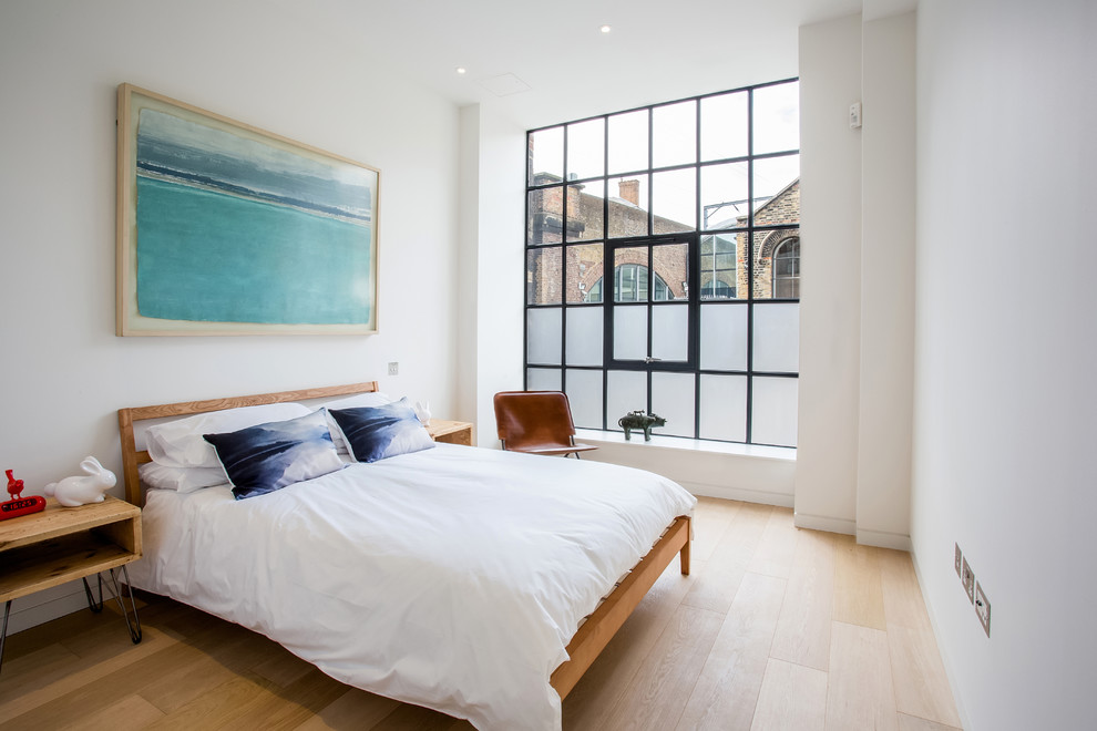 Design ideas for an industrial bedroom in London with white walls and light hardwood floors.