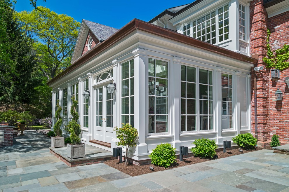 Photo of a large traditional two-storey brick white house exterior in Boston with a flat roof and a mixed roof.