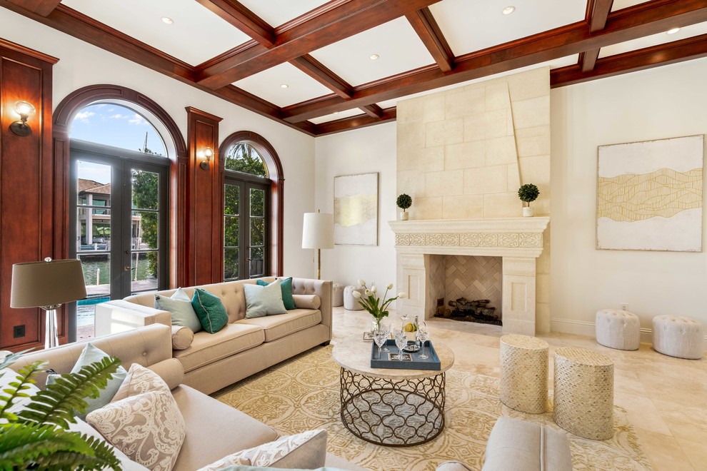 This is an example of a mediterranean living room in Miami with white walls, a standard fireplace and beige floor.