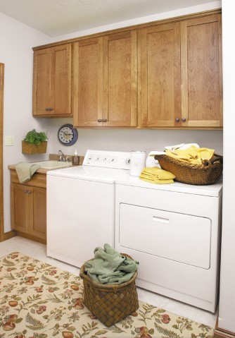 Mid-sized arts and crafts single-wall dedicated laundry room in New York with a drop-in sink, shaker cabinets, medium wood cabinets, laminate benchtops, white walls, ceramic floors, a side-by-side washer and dryer and white floor.