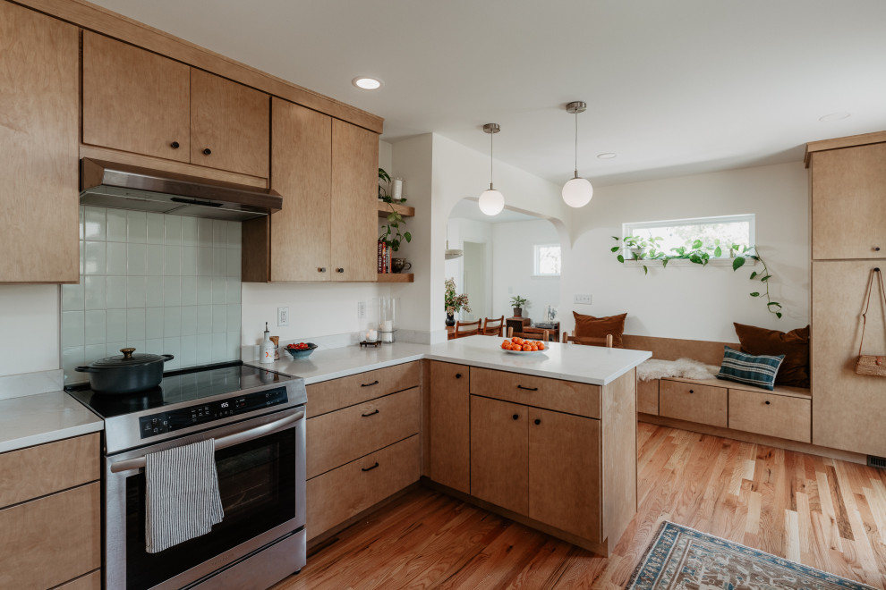 Inspiration for a mid-sized 1950s l-shaped medium tone wood floor kitchen pantry remodel in Detroit with an undermount sink, flat-panel cabinets, light wood cabinets, quartz countertops, white backsplash, quartz backsplash, stainless steel appliances, a peninsula and white countertops