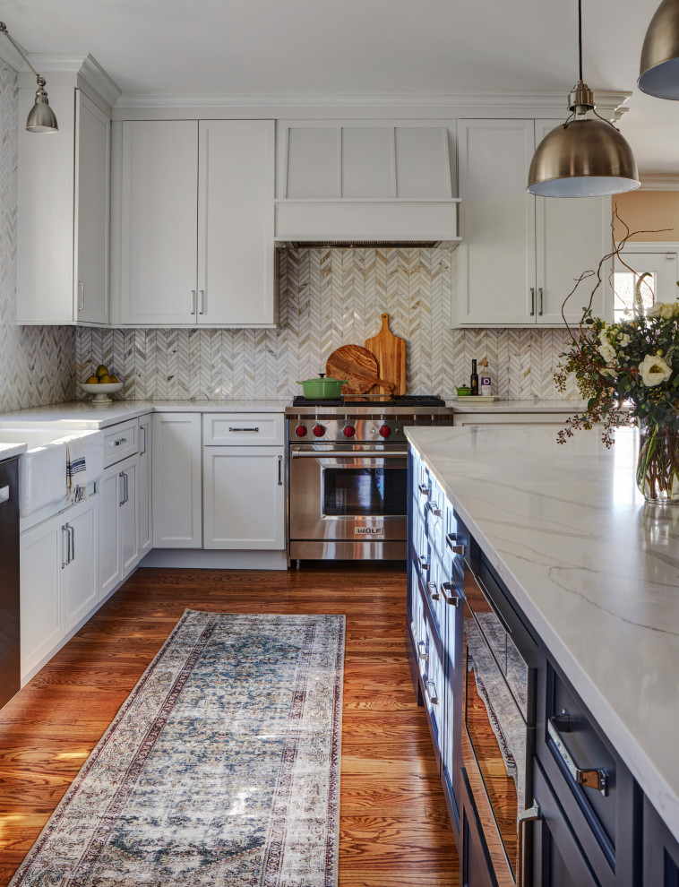 Photo of a large transitional l-shaped eat-in kitchen in Chicago with a farmhouse sink, shaker cabinets, white cabinets, quartz benchtops, multi-coloured splashback, marble splashback, stainless steel appliances, medium hardwood floors, with island, brown floor and white benchtop.