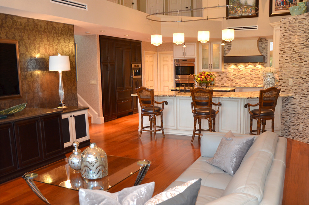 Example of a large transitional medium tone wood floor open concept kitchen design in Miami with a farmhouse sink, glass-front cabinets, white cabinets, granite countertops, multicolored backsplash, paneled appliances and an island