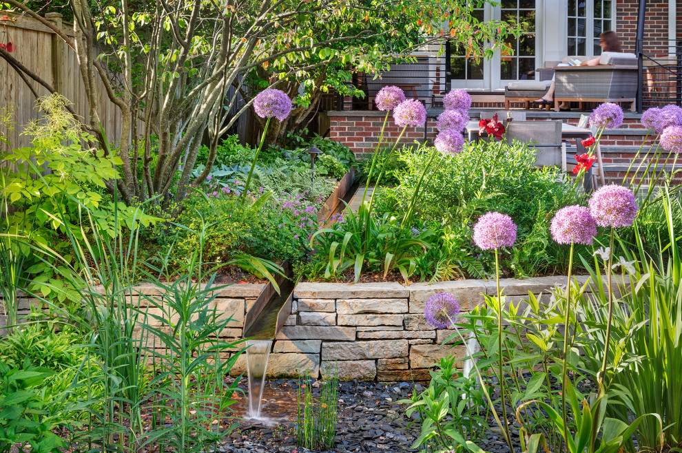 This is an example of a mid-sized modern full sun backyard river rock waterfall in Chicago.