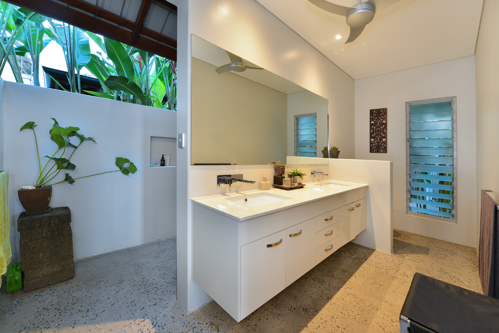 Design ideas for a tropical master bathroom in Cairns with flat-panel cabinets, white cabinets, a curbless shower, white walls, concrete floors, an undermount sink, grey floor and an open shower.