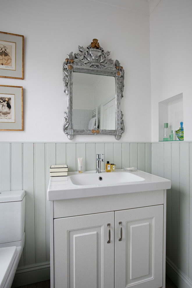 Mid-sized traditional 3/4 bathroom in London with a drop-in tub, a shower/bathtub combo, vinyl floors, an integrated sink, grey floor, raised-panel cabinets, green cabinets, a two-piece toilet, multi-coloured walls and white benchtops.