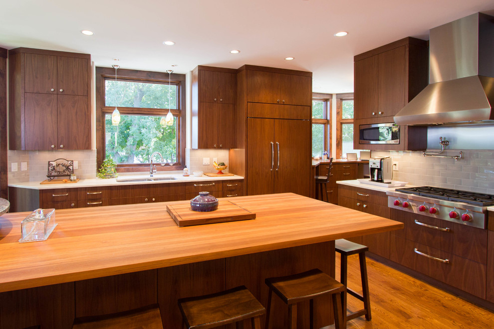 Photo of a modern l-shaped eat-in kitchen in Minneapolis with an undermount sink, medium wood cabinets, granite benchtops, grey splashback, subway tile splashback and stainless steel appliances.