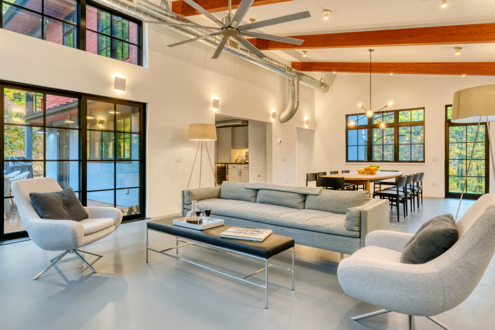 This is an example of a mid-sized contemporary open concept living room in New York with no tv, white walls, grey floor, exposed beam and vaulted.