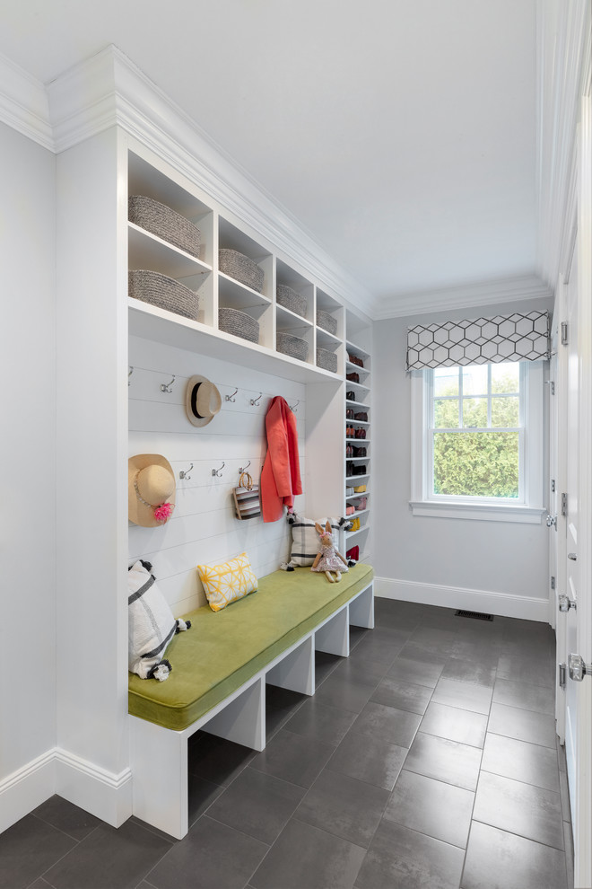 Photo of a mid-sized beach style mudroom in New York with grey walls, grey floor and porcelain floors.