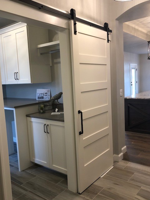 This is an example of a traditional galley laundry room in Milwaukee with flat-panel cabinets, beige cabinets, granite benchtops, grey walls, ceramic floors, a side-by-side washer and dryer and grey floor.