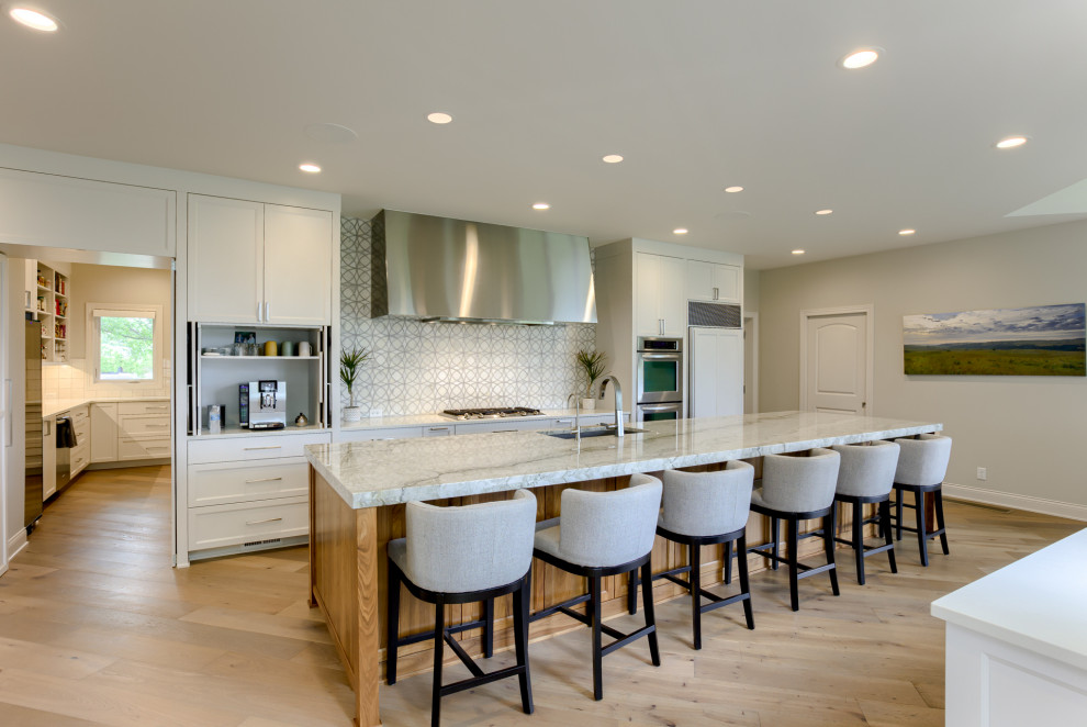 Example of a large transitional light wood floor kitchen pantry design with a single-bowl sink, recessed-panel cabinets, white cabinets, quartzite countertops, stainless steel appliances and an island