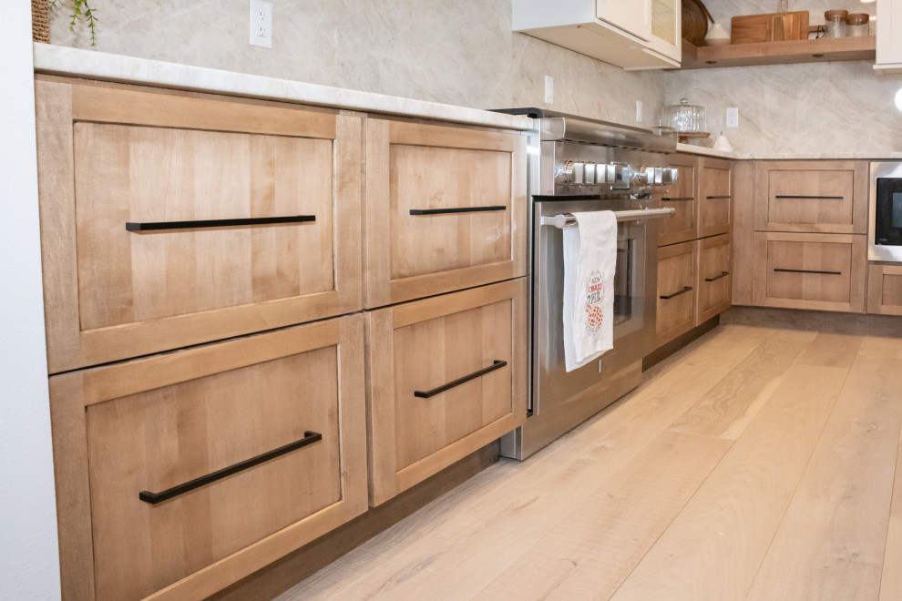 Mid-sized transitional l-shaped open plan kitchen in Other with an undermount sink, shaker cabinets, white cabinets, stainless steel appliances, with island, brown floor and vaulted.
