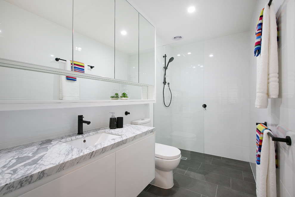 Contemporary bathroom in Melbourne with white cabinets, an open shower, porcelain tile, white walls and marble benchtops.