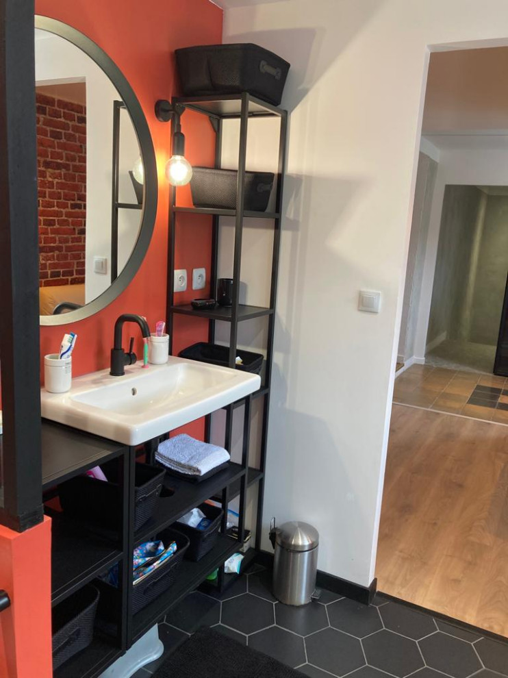 Photo of a small industrial 3/4 bathroom in Lyon with open cabinets, a curbless shower, a one-piece toilet, white tile, subway tile, orange walls, ceramic floors, a wall-mount sink, stainless steel benchtops, black floor, black benchtops, an enclosed toilet and a single vanity.