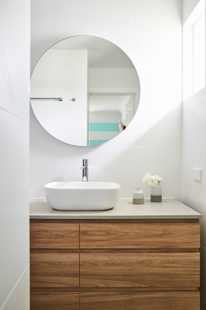This is an example of a contemporary bathroom in Sydney with flat-panel cabinets, medium wood cabinets, white tile, a vessel sink, grey benchtops and a single vanity.