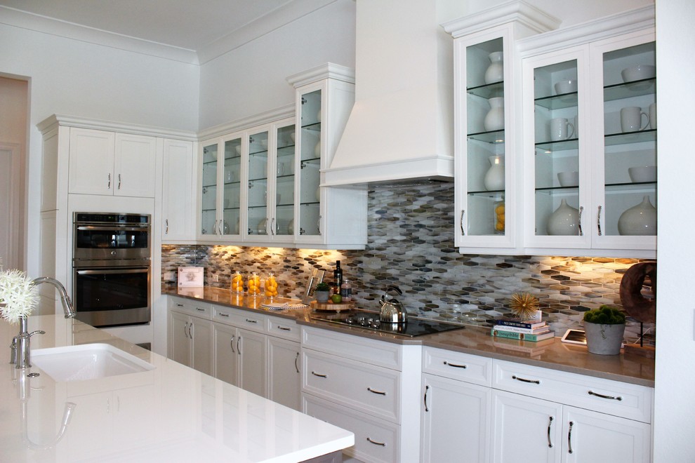 Mid-sized transitional galley eat-in kitchen photo in Tampa with an undermount sink, recessed-panel cabinets, white cabinets, quartz countertops, multicolored backsplash, glass tile backsplash, stainless steel appliances and an island