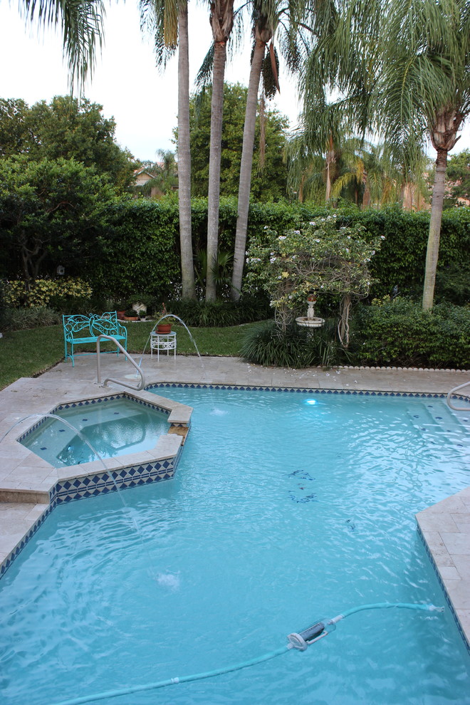 Example of a transitional backyard custom-shaped pool design in Miami with decking