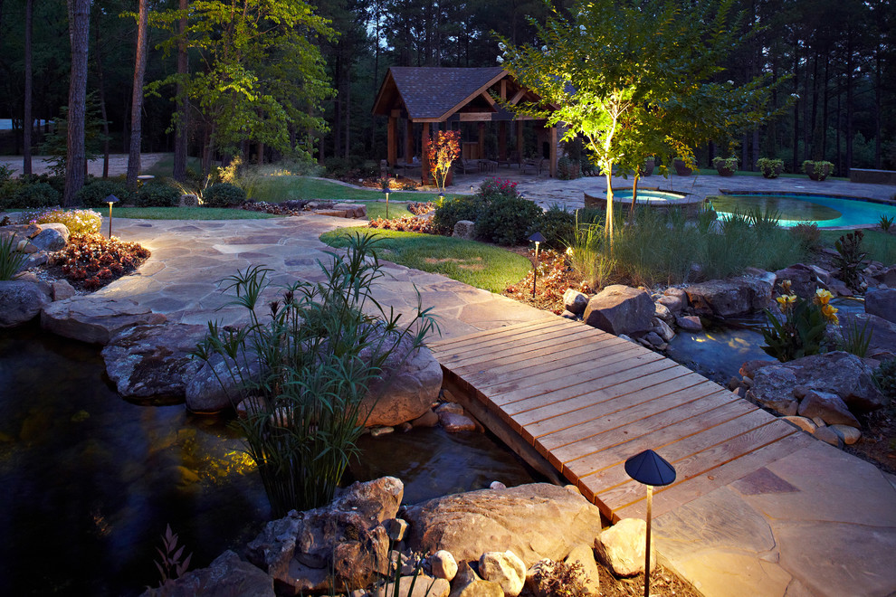 Inspiration for a mid-sized country backyard garden for summer in New Orleans with natural stone pavers and with pond.