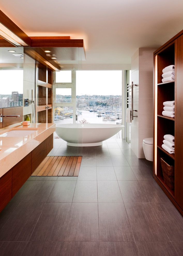 Photo of a contemporary bathroom in Vancouver with a freestanding tub, an undermount sink, flat-panel cabinets, medium wood cabinets, granite benchtops, an open shower, a wall-mount toilet, an open shower and orange benchtops.