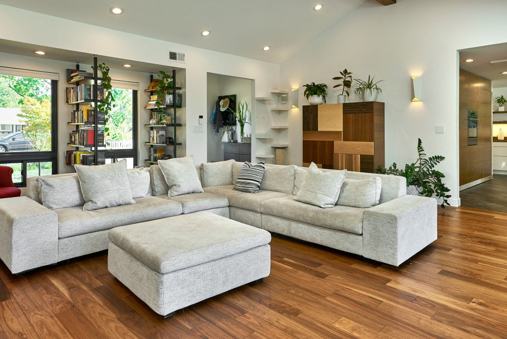 Foto di un soggiorno minimalista di medie dimensioni e aperto con libreria, pareti bianche, pavimento in legno massello medio, pavimento marrone e soffitto a volta