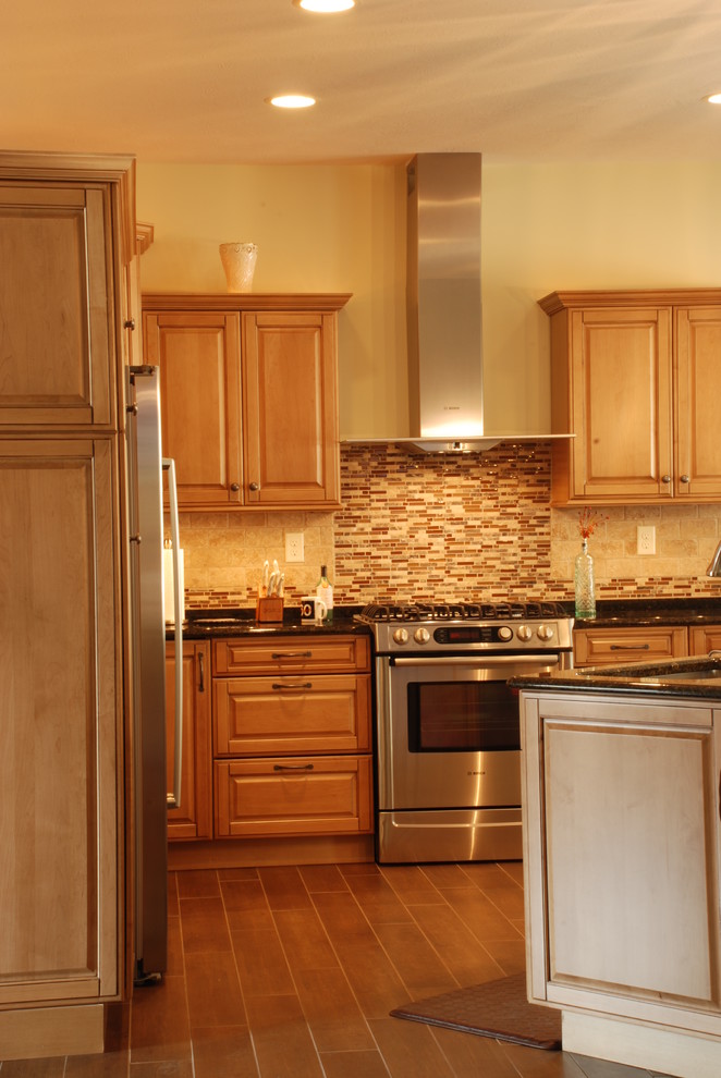 Eat-in kitchen - mid-sized transitional l-shaped ceramic tile eat-in kitchen idea with a farmhouse sink, raised-panel cabinets, medium tone wood cabinets, granite countertops, beige backsplash, ceramic backsplash, stainless steel appliances and an island