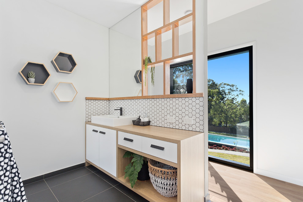 This is an example of a contemporary kids bathroom in Sunshine Coast with furniture-like cabinets, laminate benchtops, light wood cabinets, white tile and a vessel sink.