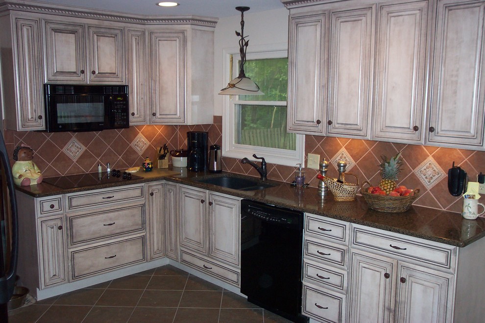Mid-sized transitional l-shaped kitchen pantry photo in Detroit with a single-bowl sink, raised-panel cabinets, beige cabinets, granite countertops, brown backsplash, stone tile backsplash and black appliances