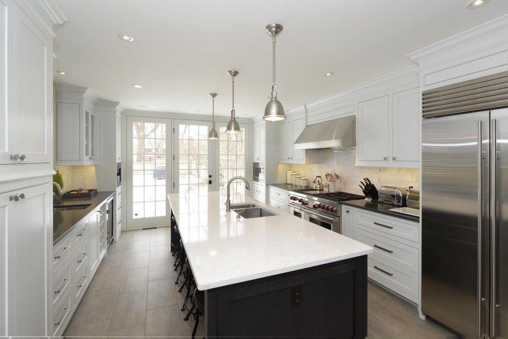 Minimalist brown floor eat-in kitchen photo with an integrated sink, yellow cabinets, quartzite countertops, white backsplash, stainless steel appliances, an island and black countertops