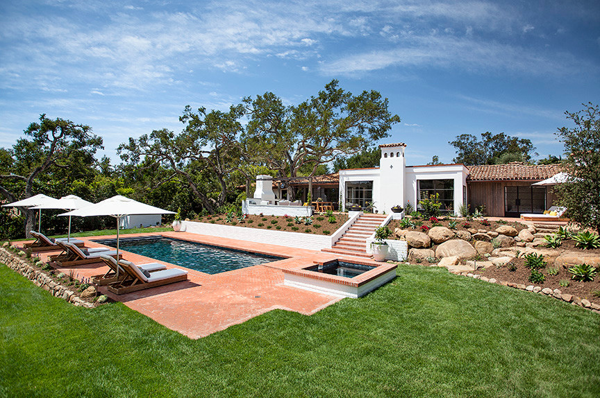 This is an example of a large mediterranean backyard rectangular lap pool in Santa Barbara with a hot tub and brick pavers.