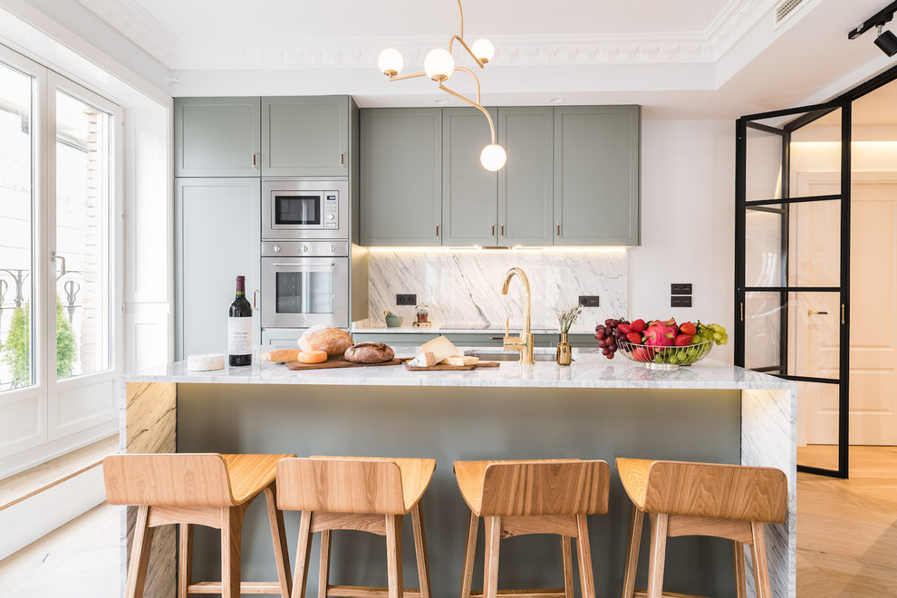 Inspiration for a contemporary galley eat-in kitchen in Madrid with an undermount sink, shaker cabinets, green cabinets, marble benchtops, grey splashback, marble splashback, stainless steel appliances, light hardwood floors, with island, beige floor and grey benchtop.