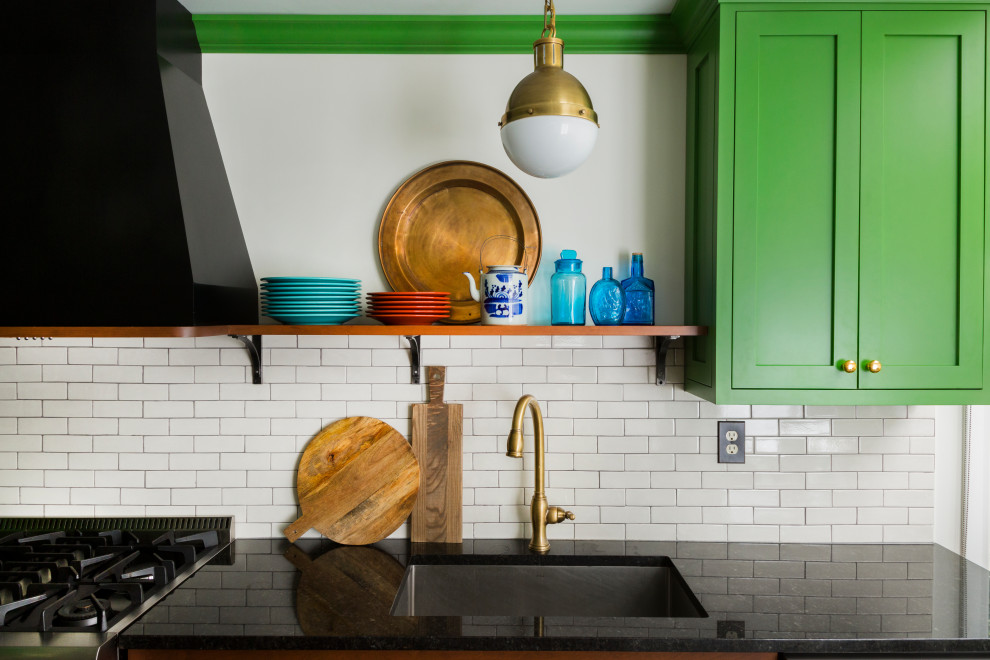 Photo of a mid-sized eclectic l-shaped eat-in kitchen in Philadelphia with an undermount sink, shaker cabinets, green cabinets, granite benchtops, white splashback, ceramic splashback, stainless steel appliances, slate floors, with island, green floor and black benchtop.