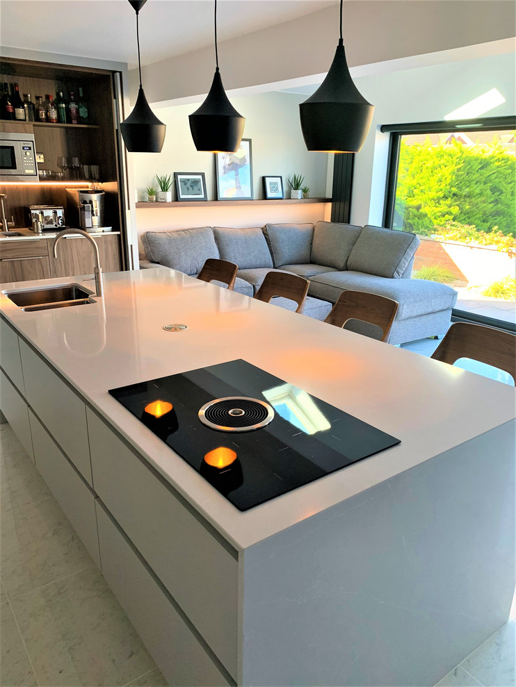 Large contemporary l-shaped open plan kitchen in Other with a drop-in sink, flat-panel cabinets, dark wood cabinets, quartz benchtops, black appliances, porcelain floors and with island.
