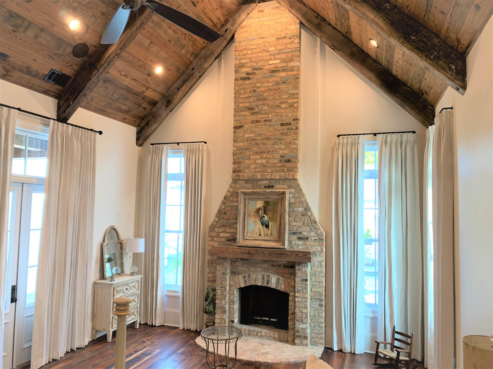 Inspiration for a large timeless master medium tone wood floor and exposed beam bedroom remodel in New Orleans with white walls, a standard fireplace and a brick fireplace