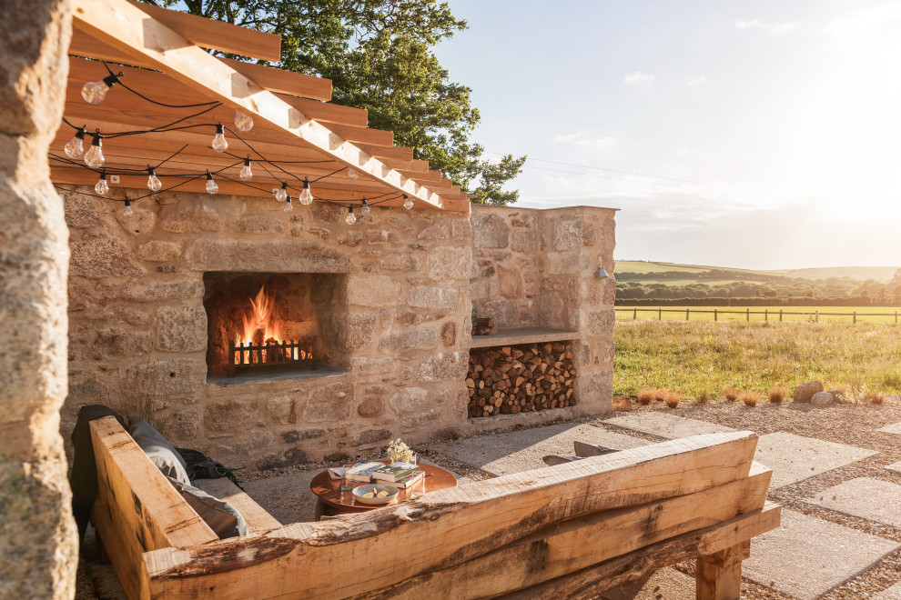 Mittelgroße Landhausstil Pergola hinter dem Haus mit Feuerstelle und Natursteinplatten in Cornwall