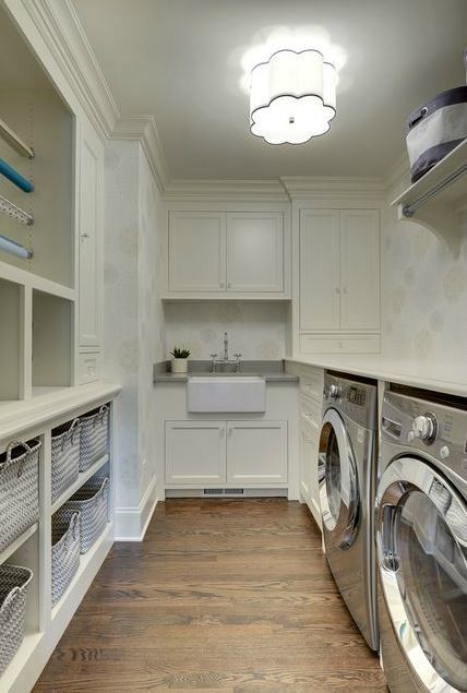 Design ideas for a mid-sized traditional galley utility room in Minneapolis with a farmhouse sink, shaker cabinets, white cabinets, solid surface benchtops, white walls, dark hardwood floors and a side-by-side washer and dryer.