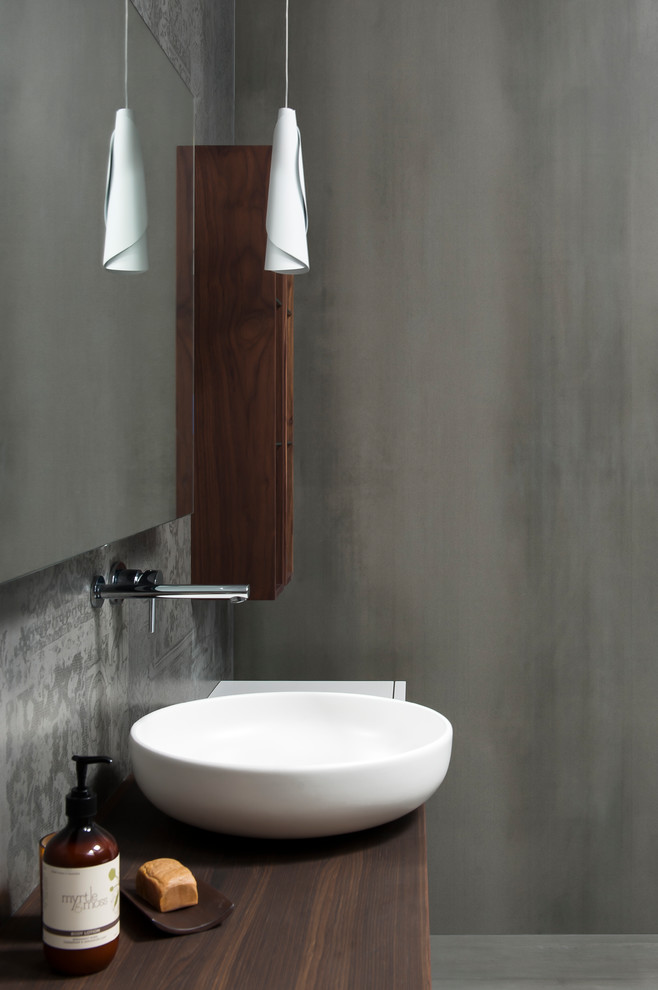 Design ideas for a mid-sized modern master wet room bathroom in Sydney with furniture-like cabinets, white cabinets, a freestanding tub, a wall-mount toilet, gray tile, porcelain tile, grey walls, porcelain floors, a vessel sink, wood benchtops, grey floor and an open shower.